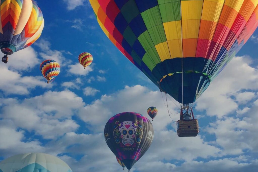 Kleurrijke luchtballonnen zweven door een wolkenlucht tijdens een ballonvaart