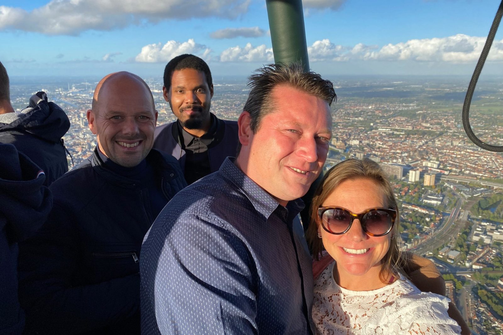 Passagiers genieten van een ballonvaart boven Gent met uitzicht op het landschap