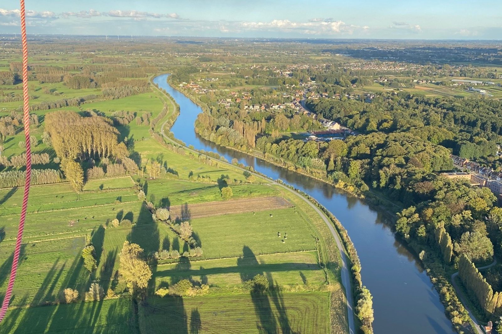 Panoramisch uitzicht over de rivier en velden tijdens een ballonvlucht in Oost-Vlaanderen