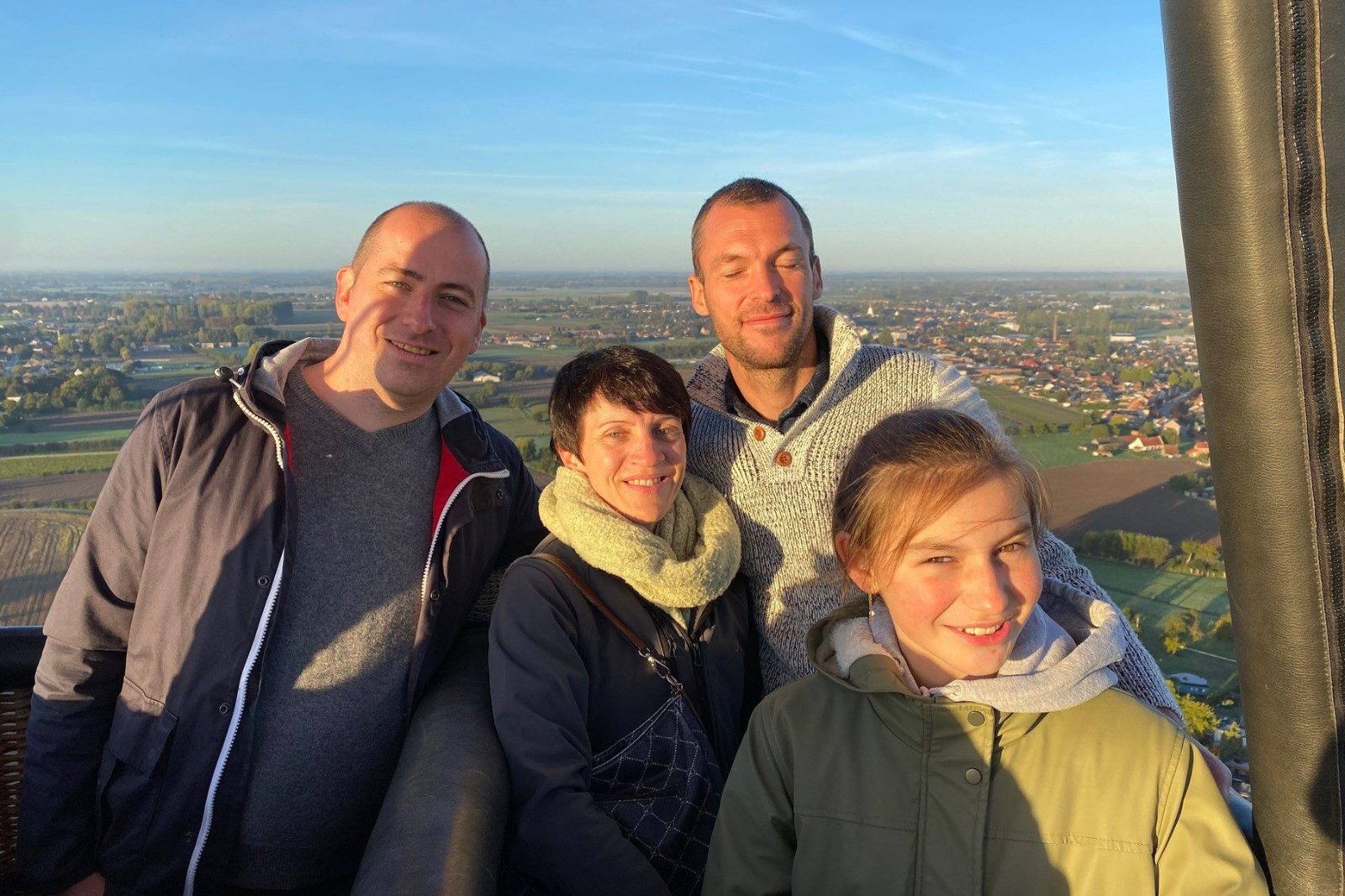 Groep geniet van een ballonvaart boven Oost-Vlaanderen bij zonsondergang