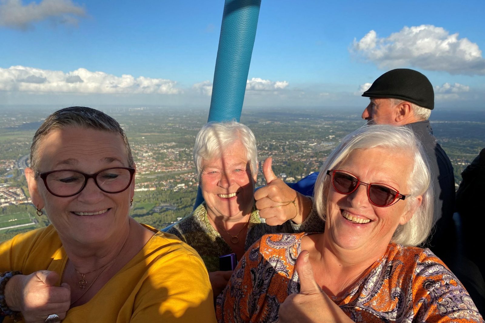 Vrolijke passagiers genieten van het uitzicht tijdens een ballonvaart boven Deinze