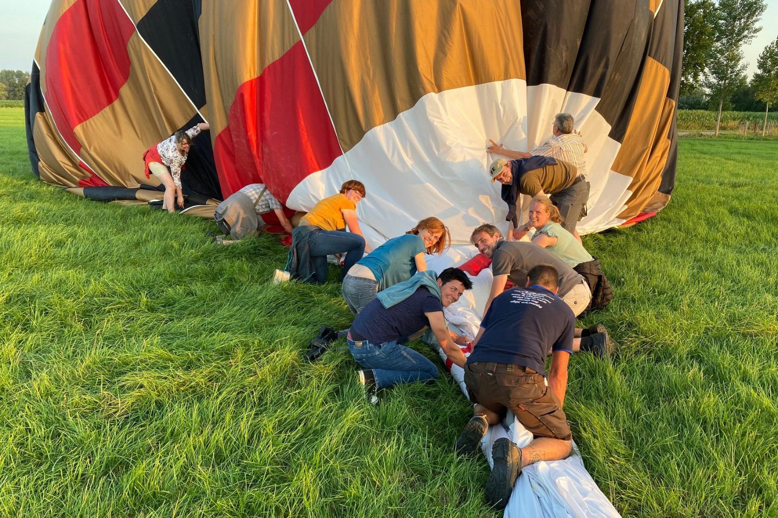 Een groep helpt mee bij het inpakken van de luchtballon na de landing in Deinze