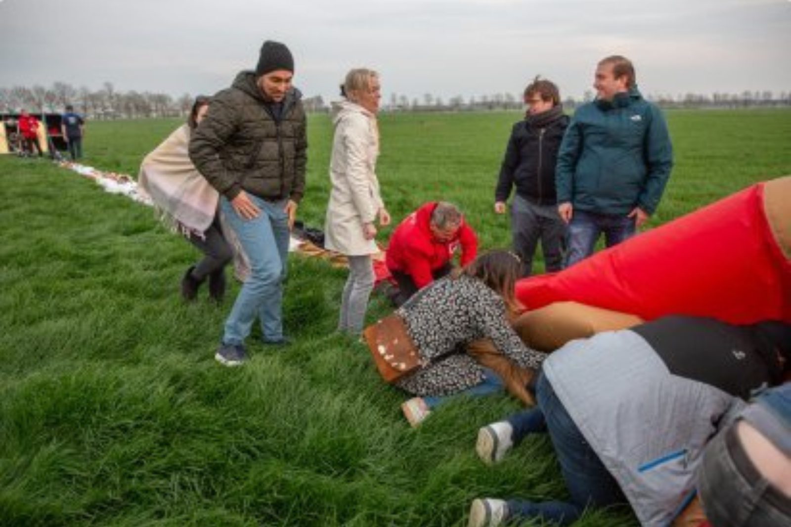 Mensen helpen mee bij het inpakken van de luchtballon na de landing in Lochristi