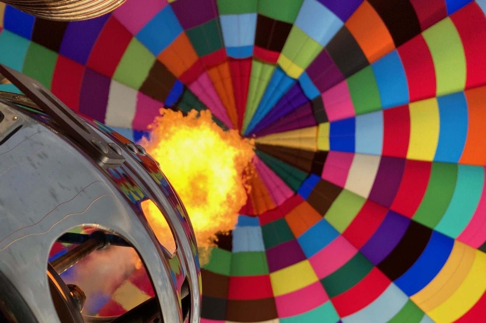 Vlam verwarmt de kleurrijke luchtballon tijdens een ballonvaart in Zelzate