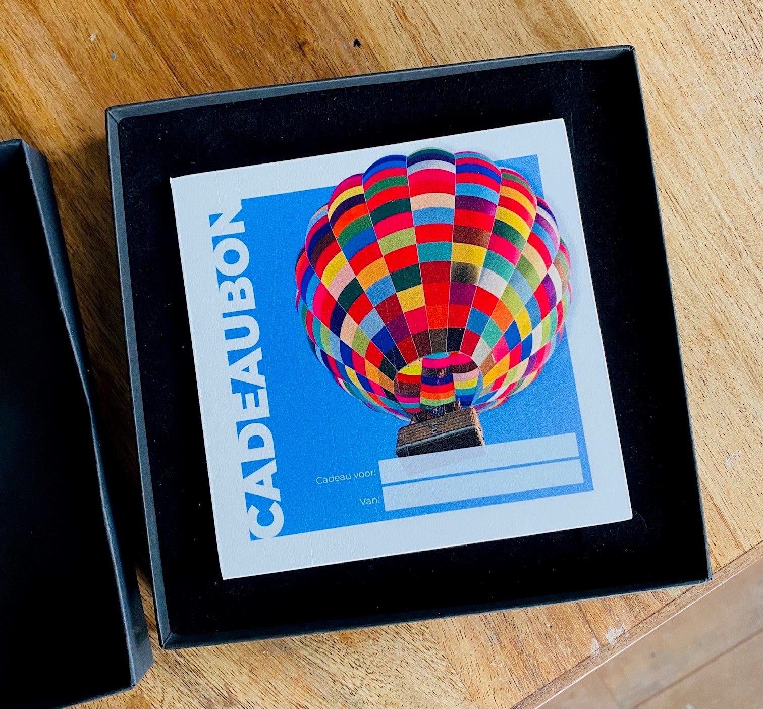 Een kleurrijke cadeaubon voor een ballonvaart, mooi verpakt om cadeau te geven