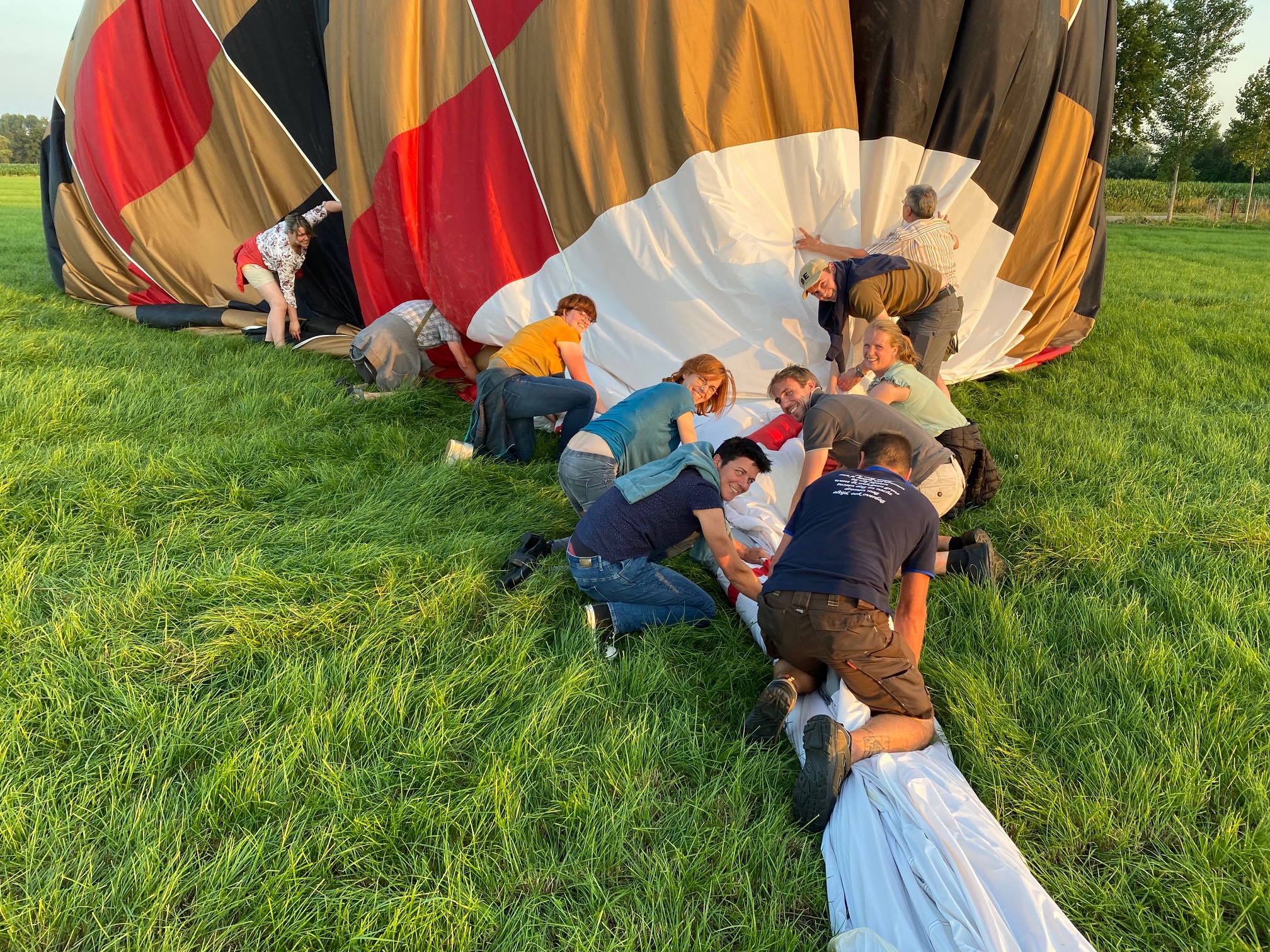 Deelnemers werken samen om de luchtballon op te plooien — een uniek teambuildingmoment dat je met een ballonvaart-cadeaubon cadeau kunt doen