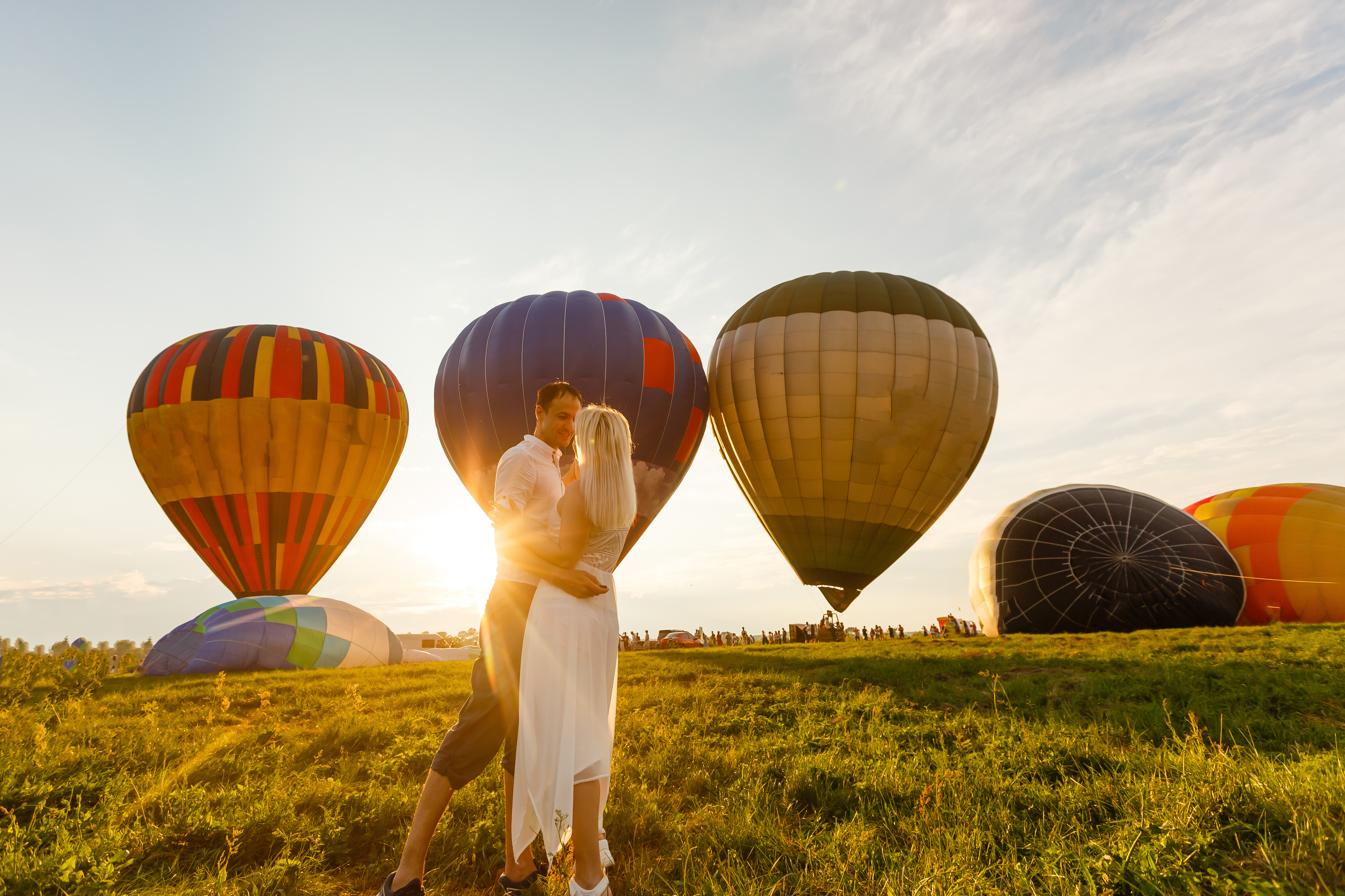 Koppel geniet van een romantisch moment bij zonsondergang tussen luchtballonnen tijdens een huwelijksaanzoek