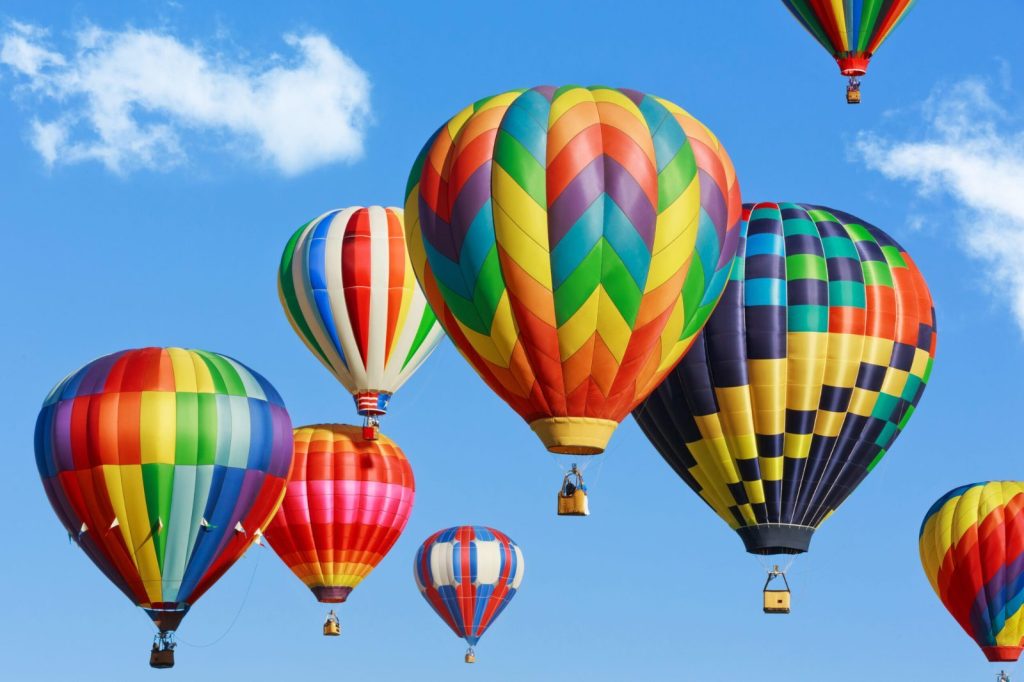 Meerdere kleurrijke luchtballonnen in de lucht tijdens een ballonvaart bij helder weer