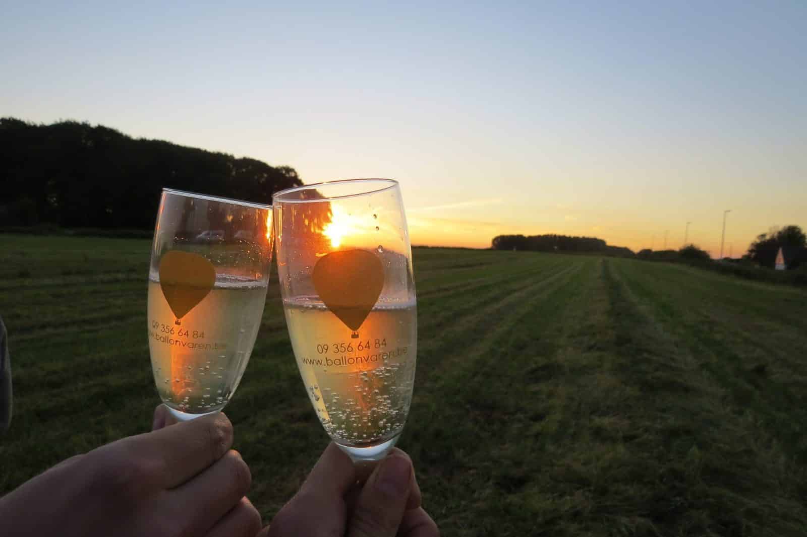 Champagneglazen tijdens een romantisch huwelijksaanzoek na een ballonvaart bij zonsondergang.