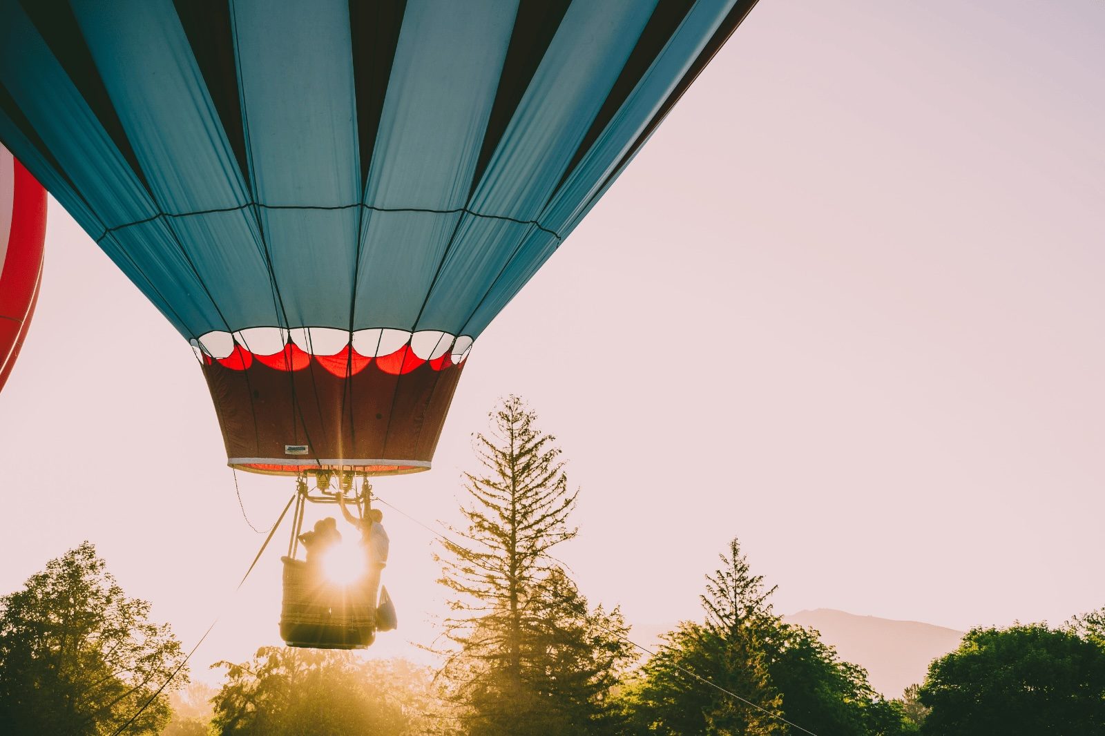 Luchtballon stijgt op bij zonsopgang boven bomen tijdens een rustige ballonvaart met ontbijt
