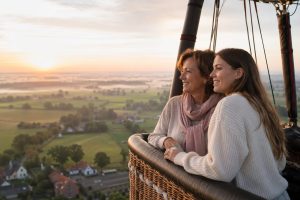 Moeder en dochter kijken samen uit over de mistige velden tijdens een ballonvaart bij zonsopgang